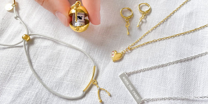 A flatly of our minimal pieces over a white background, with a hand holding an open locket.